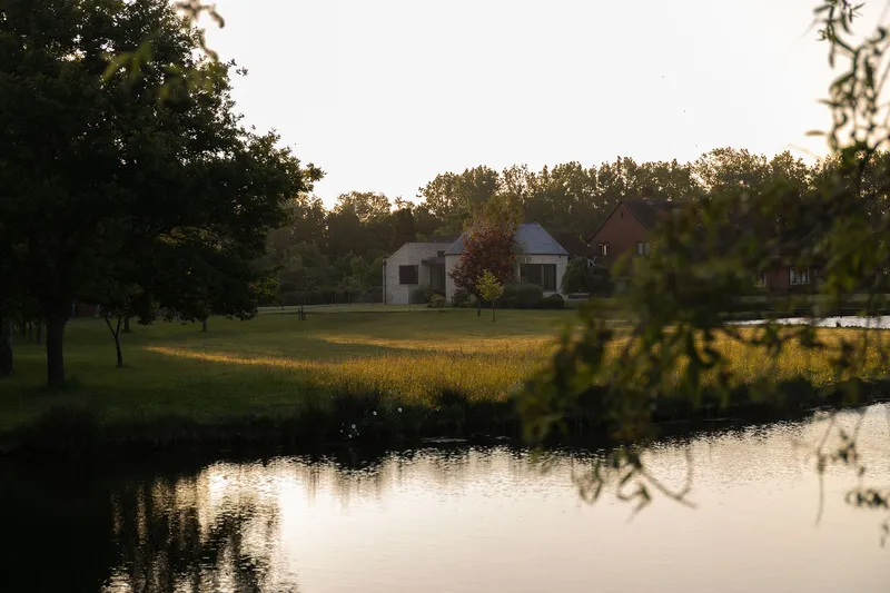 Distant view across the still pond at golden hour with tree reflections in the water