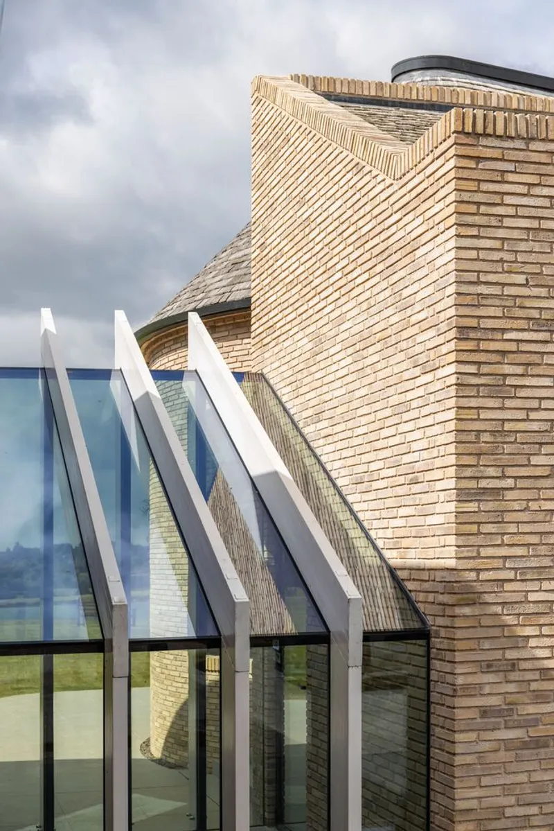 Angled glazing with white metal fins against curved and corbelled brickwork