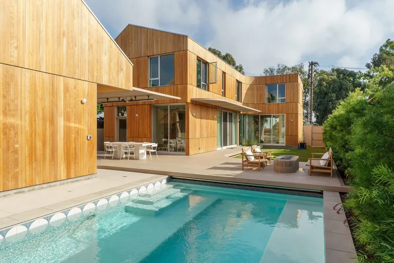 Rear facade with vertical timber cladding and swimming pool framed by mature trees