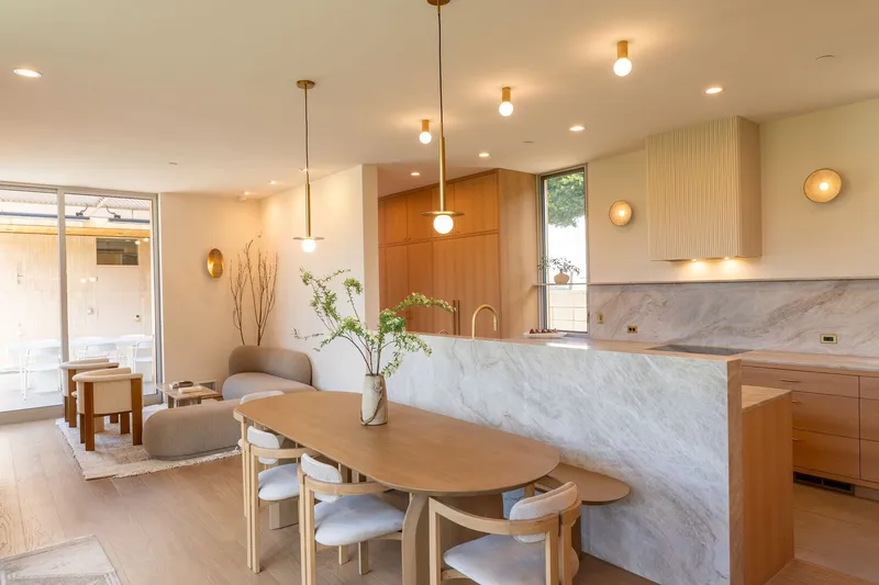 Open kitchen and dining space with marble island and brass pendant lights