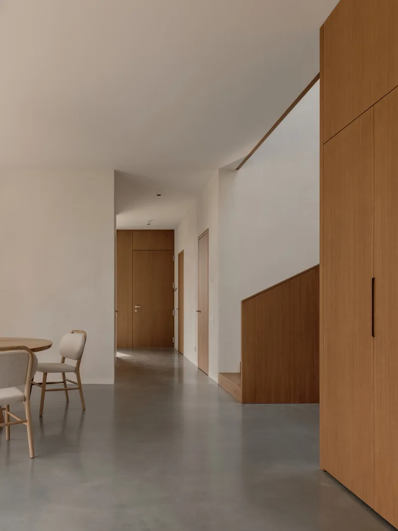 Hallway with grey polished concrete floor and timber-clad stair enclosure in soft daylight