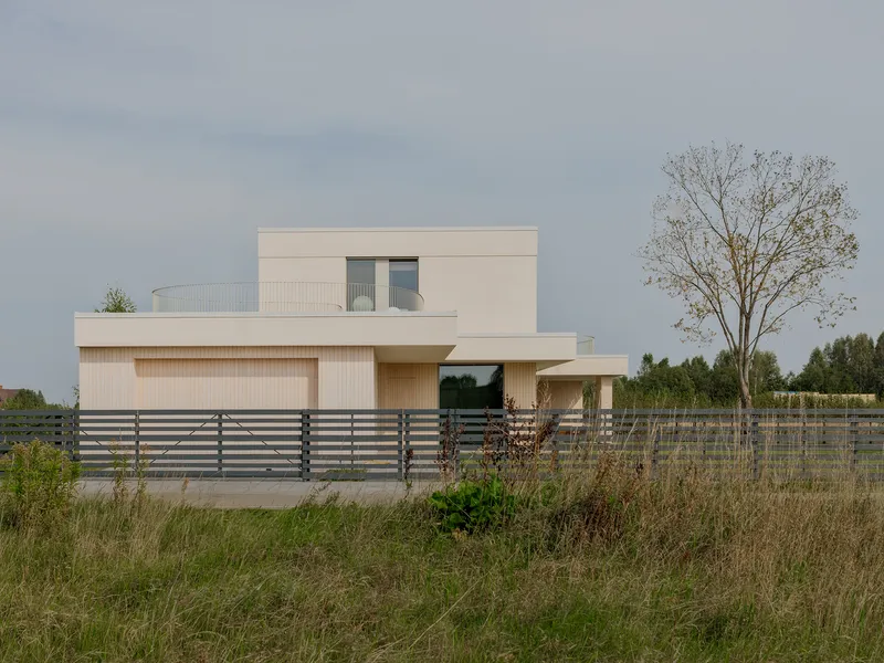 Street view of the stacked volumes with vertical timber cladding and horizontal slat fence fronting grassland
