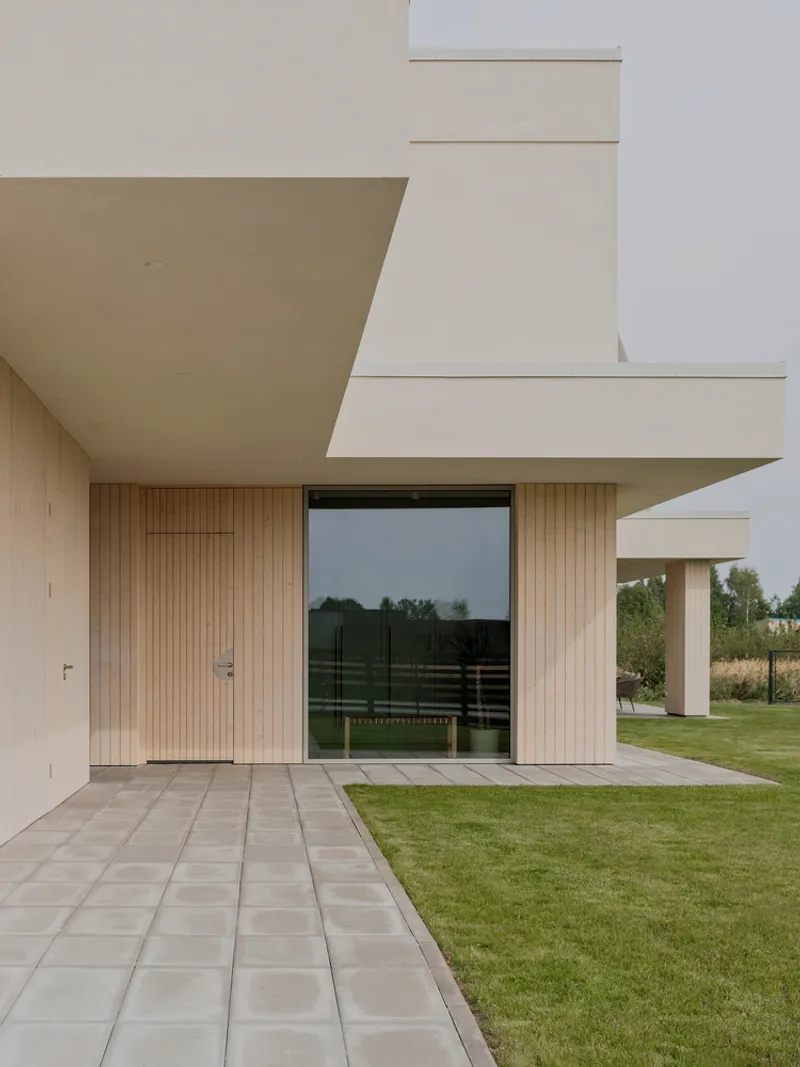 Covered terrace with pale stone paving and vertical wood cladding alongside a lawn