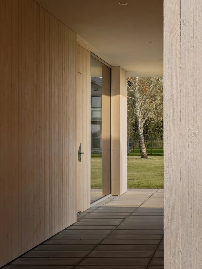 Entry corridor with timber-clad door and slatted flooring framing a view to the garden