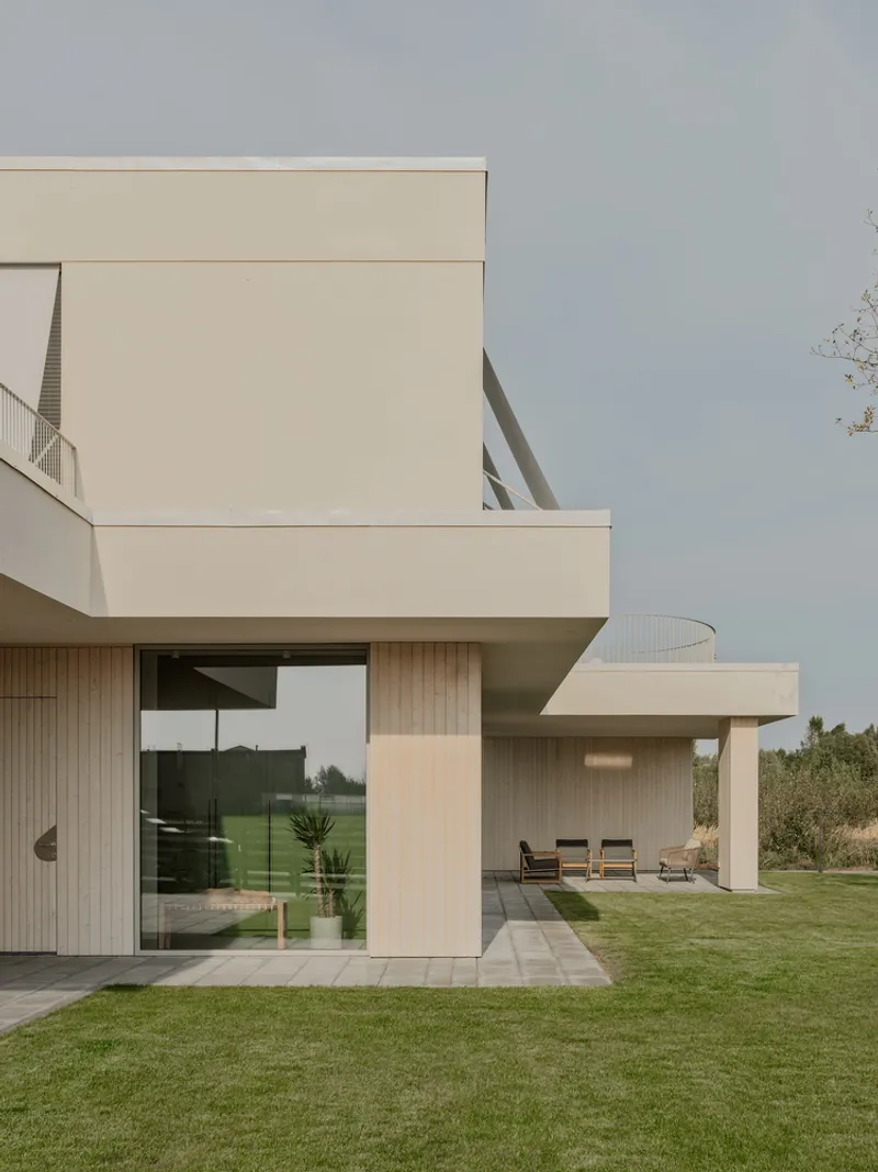 Corner view of interlocking volumes with large glazing opening onto a lawn terrace