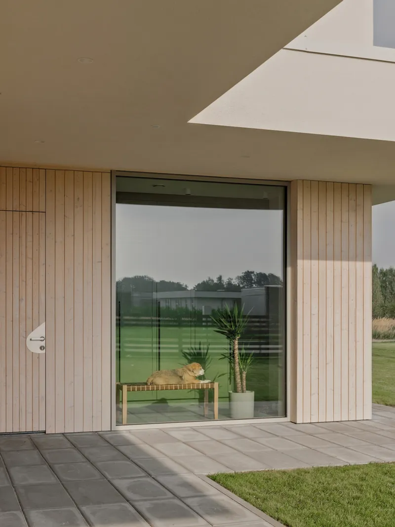 Terrace corner with timber-clad walls and wide sliding glass door reflecting garden and sky