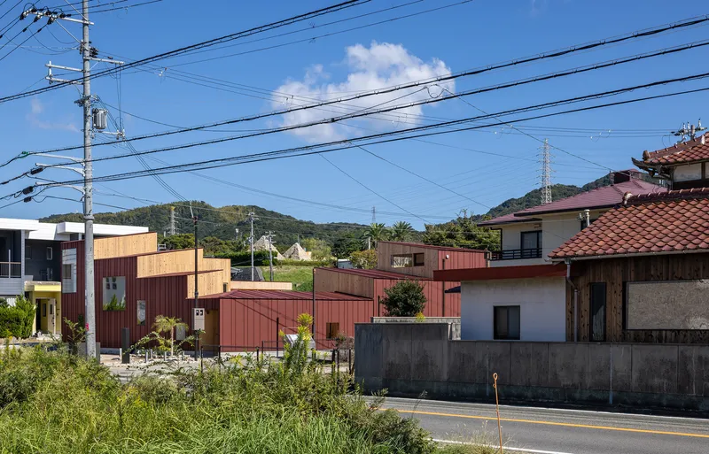 Street view showing timber and corrugated metal facades among neighboring houses beneath overhead power lines