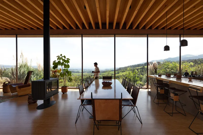 Dining room with floor-to-ceiling glazing overlooking the landscape and exposed timber ceiling joists