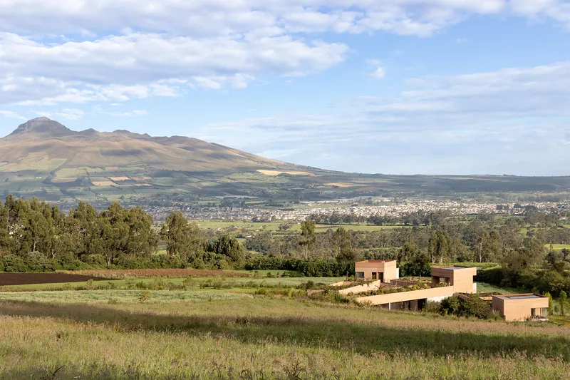 Distant view of the clustered rammed earth buildings set in agricultural fields below mountains