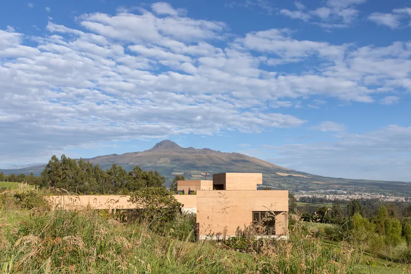 Stepped rammed earth facade overlooking a distant mountain range under afternoon light