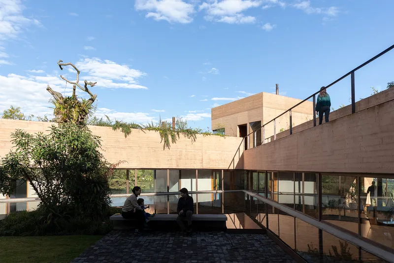Steel stair ascending past planted courtyard with figures seated and standing in afternoon light