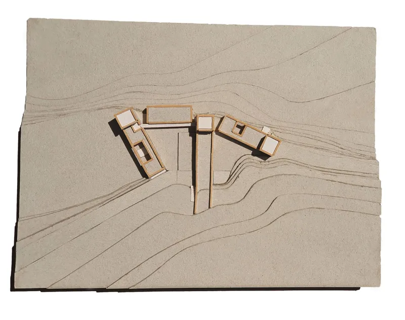 Physical site model showing building volumes set into terraced topography with contour lines
