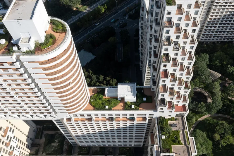 Aerial view of courtyard formed by four residential towers with stepped balconies and rooftop gardens