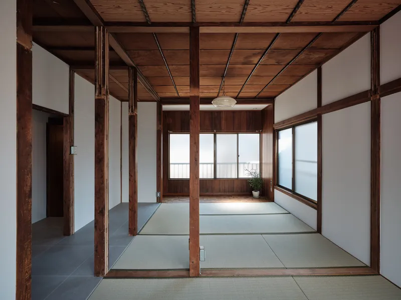 Tatami-floored rooms separated by timber post-and-beam structure with exposed wood ceiling and sliding screens