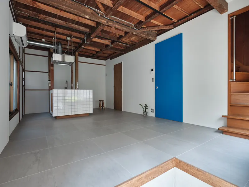 View across grey tile floor toward blue accent wall and timber staircase at right