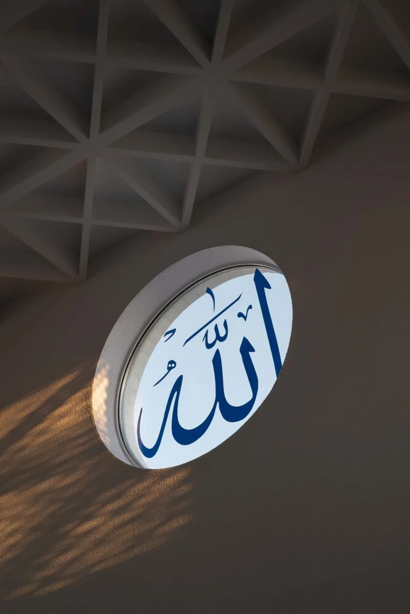 Circular backlit calligraphic window projecting shadow patterns below a geometric coffered ceiling