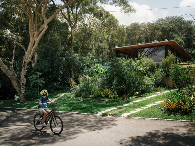 Street view of the planted front lawn with stepping stones as a child cycles past