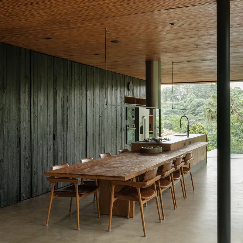 Dining table and kitchen counter under timber ceiling with reclaimed wood wall and view toward hillside