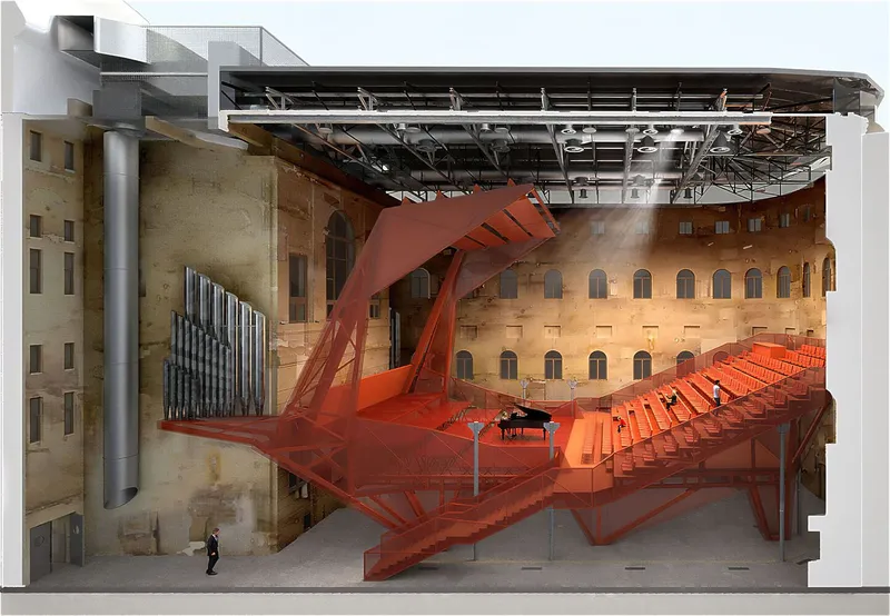 Sectional model view of the red steel auditorium insert with organ pipes against sandstone walls