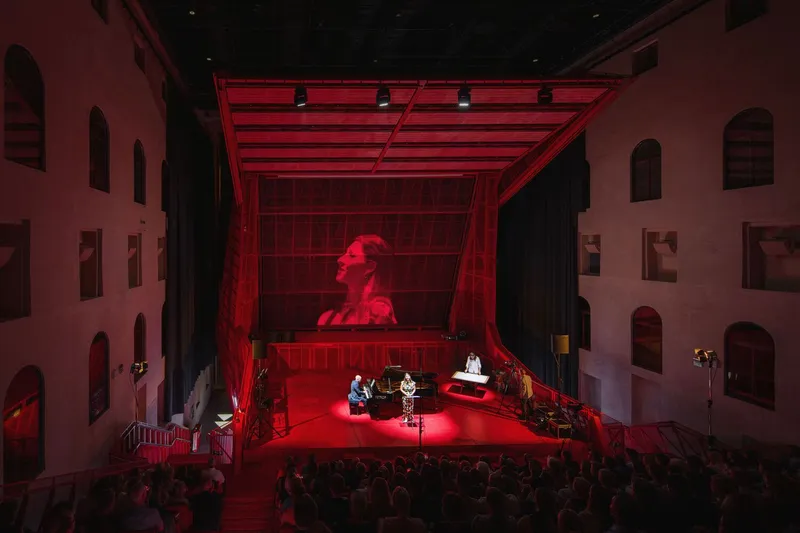 Theatre courtyard during a performance with musicians on stage and audience gathered below