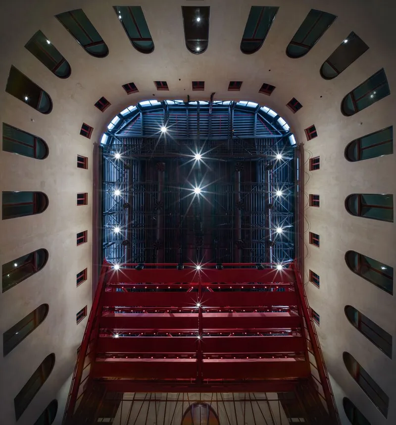 Looking up through central atrium showing red steel balconies and concrete walls with curved window openings
