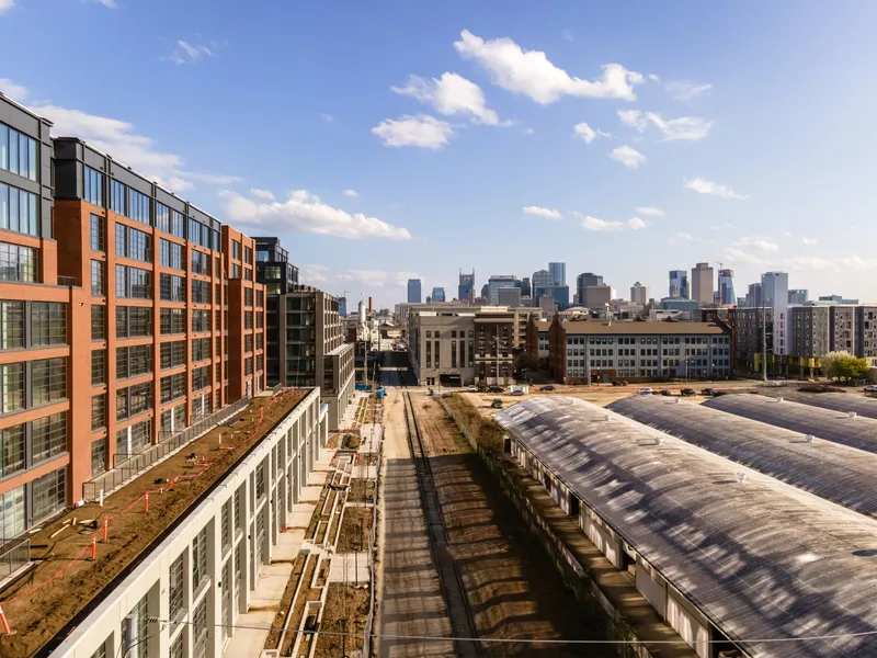 Rooftop view of green roofs and translucent barrel-vault skylight structures with city skyline beyond