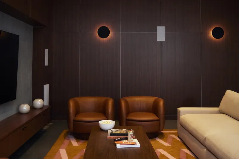 Seating lounge with dark wood wall panels, circular wall sconces, and patterned area rug