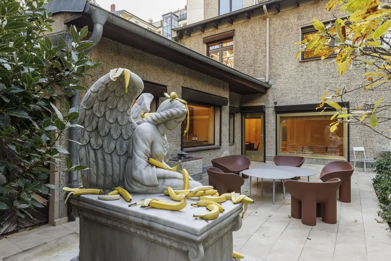 Courtyard terrace with eagle sculpture on pedestal surrounded by autumn foliage and dining furniture
