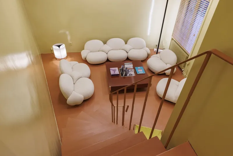 View down the open staircase toward lounge area with rounded upholstered seating and timber side table