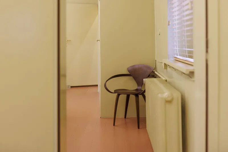 Wooden curved-back chair beside a radiator near a window with venetian blinds