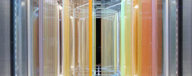 Head-on view of the entrance framed by vertical translucent panels in warm amber and green tones