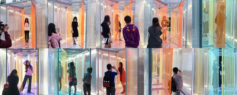 Interior view of translucent panels creating individual chambers with visitors walking through illuminated color-shifting spaces