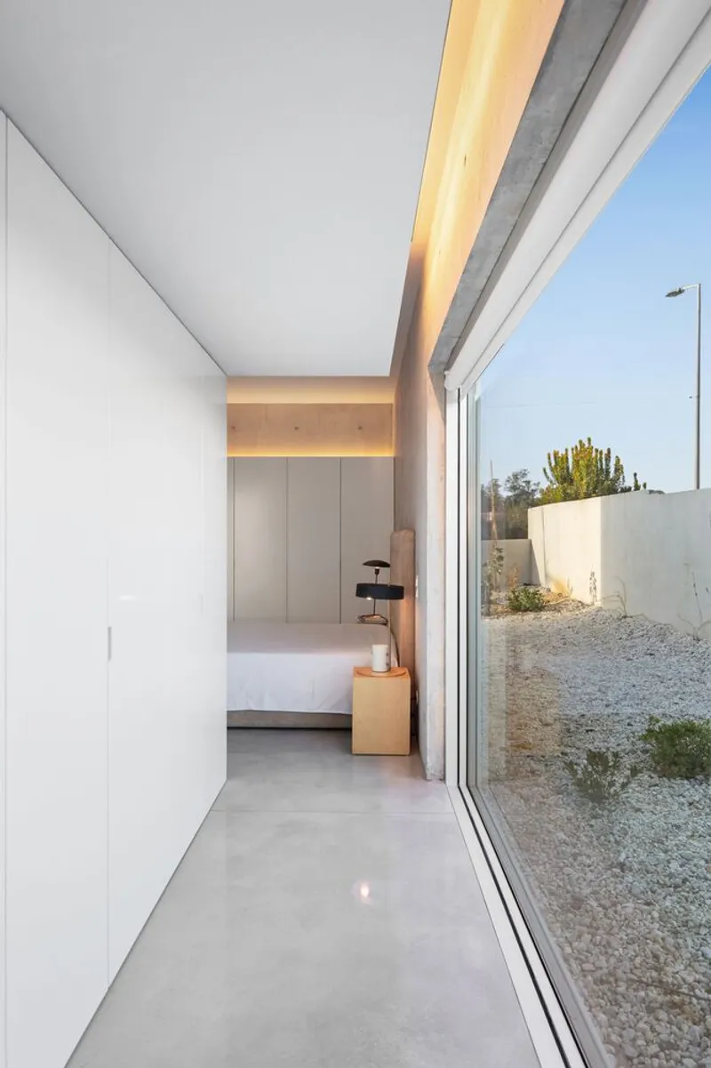 Interior corridor with full-height glazing opening to a gravel courtyard and polished concrete floor