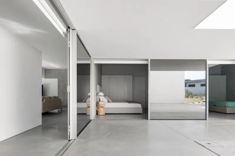 View through sliding glass doors into bedroom with grey cabinetry and polished concrete floor
