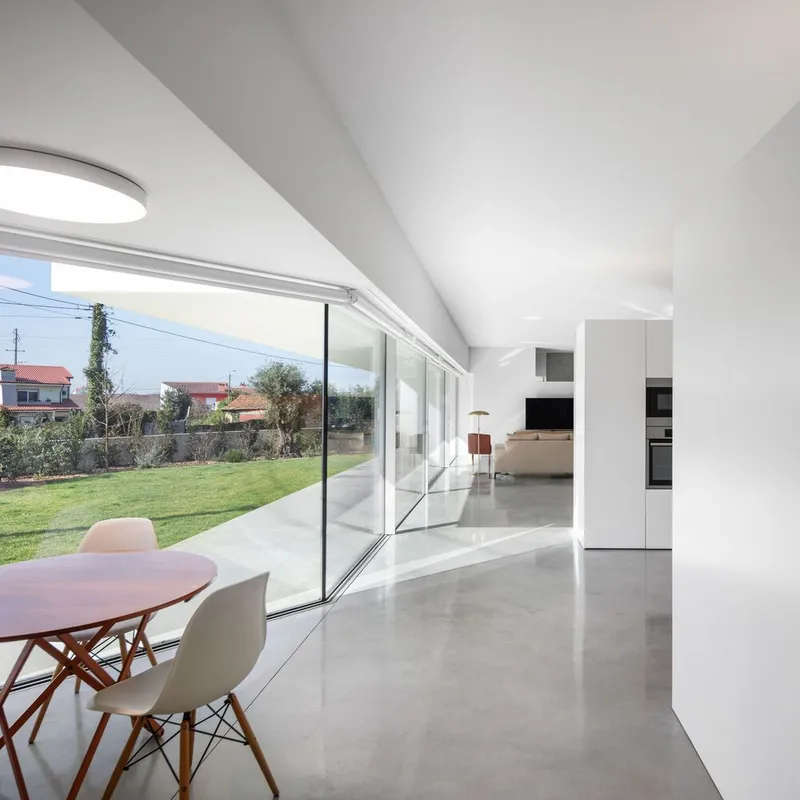 Open plan living space with vaulted ceiling and floor-to-ceiling glazing overlooking garden