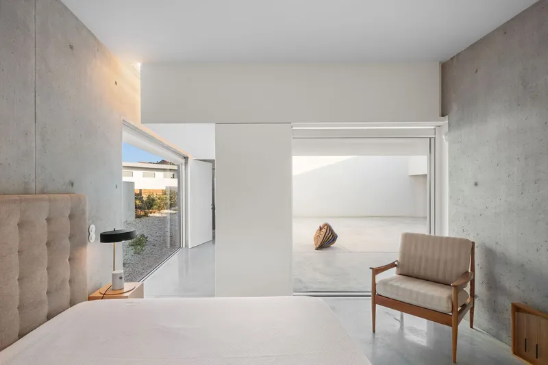 Bedroom with sliding partition wall opening to hallway and concrete wall surfaces