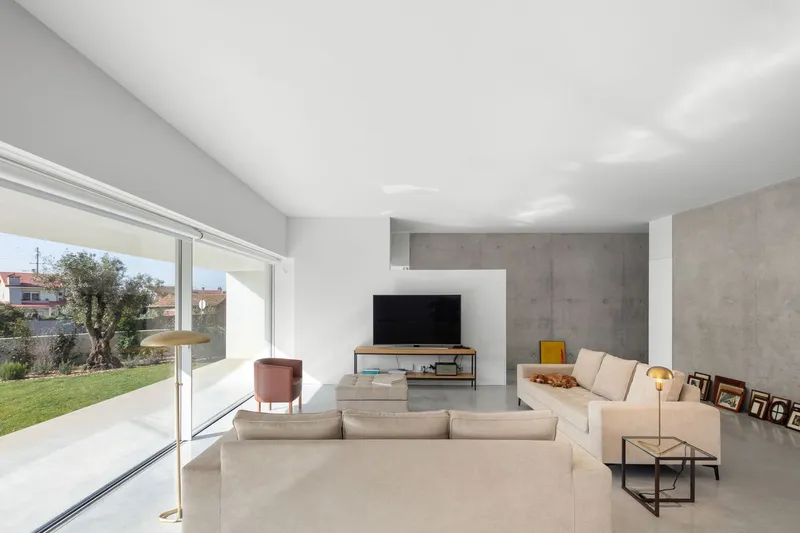 Living room with concrete accent walls and full-height glazing opening to the garden