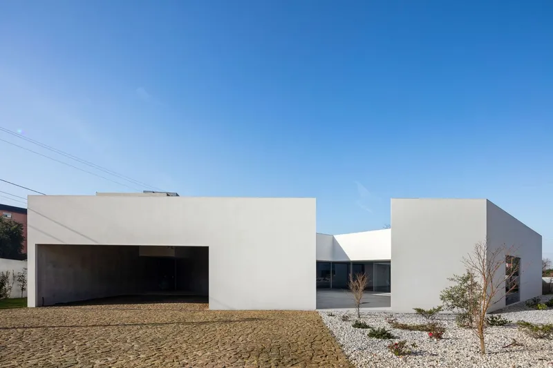 Street-facing facade with recessed garage opening and white gravel landscape under power lines