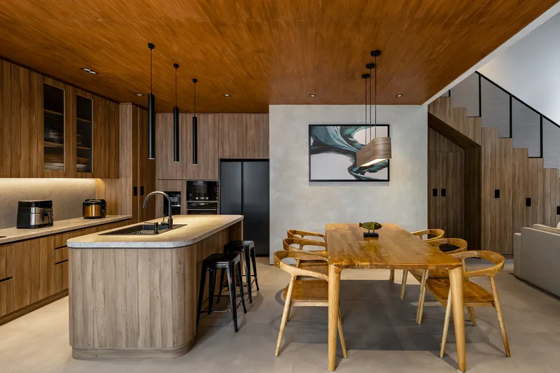 Open kitchen and dining area with curved timber ceiling and island counter under pendant lights