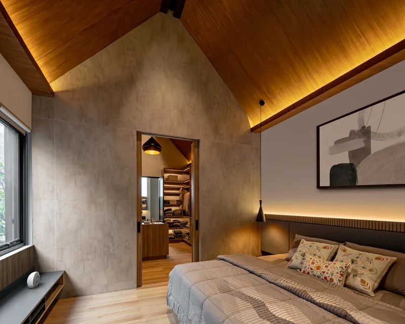 Bedroom with vaulted timber ceiling, concrete walls and view through doorway to walk-in closet