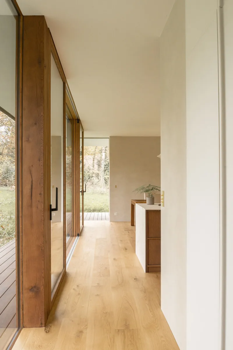 Hallway with timber sliding doors and white walls opening toward garden view in autumn light