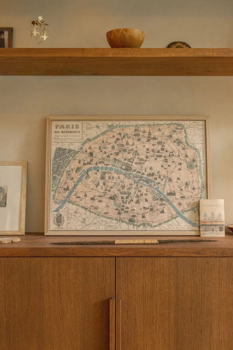 Timber shelving unit displaying a framed vintage map and woven bowl against a white wall