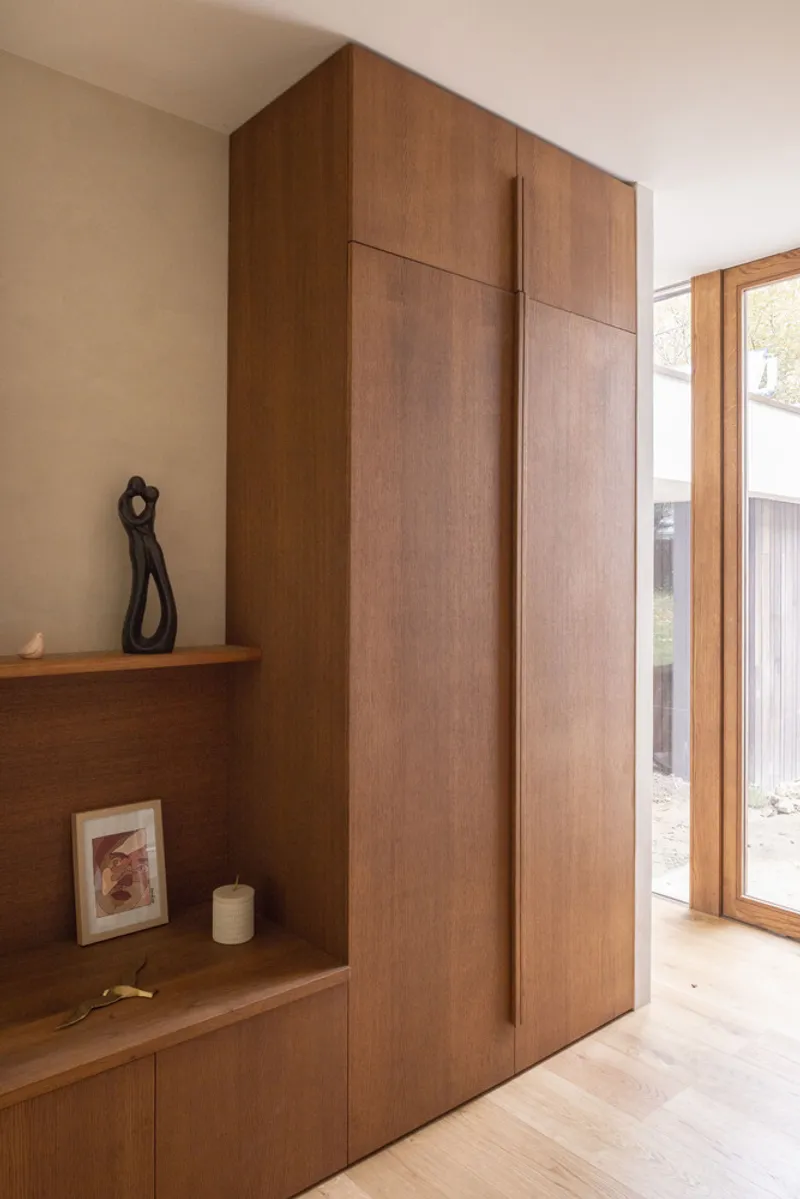 Timber wardrobe wall with integrated shelf and vertical pull detail next to oak flooring