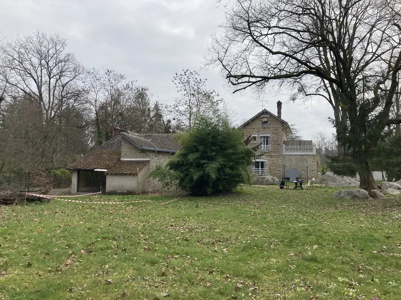 View of the stone house and outbuildings across the lawn on an overcast day