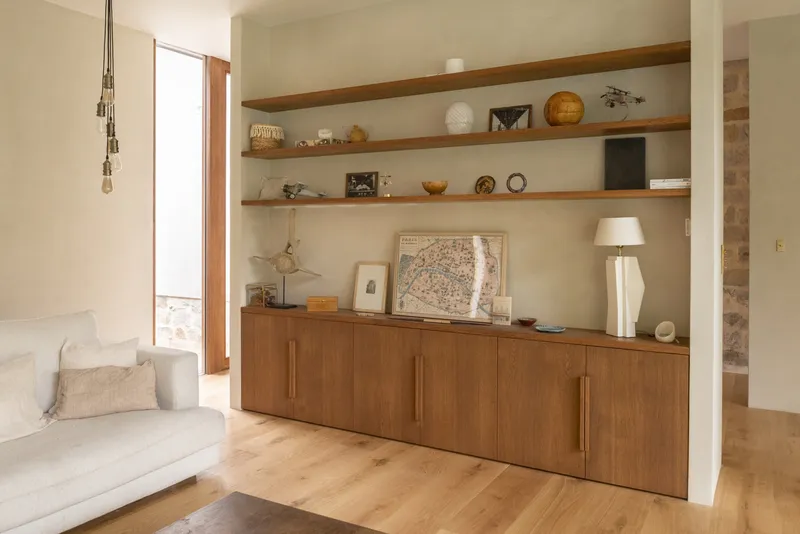Built-in timber credenza with floating shelves displaying objects in a living room with oak flooring