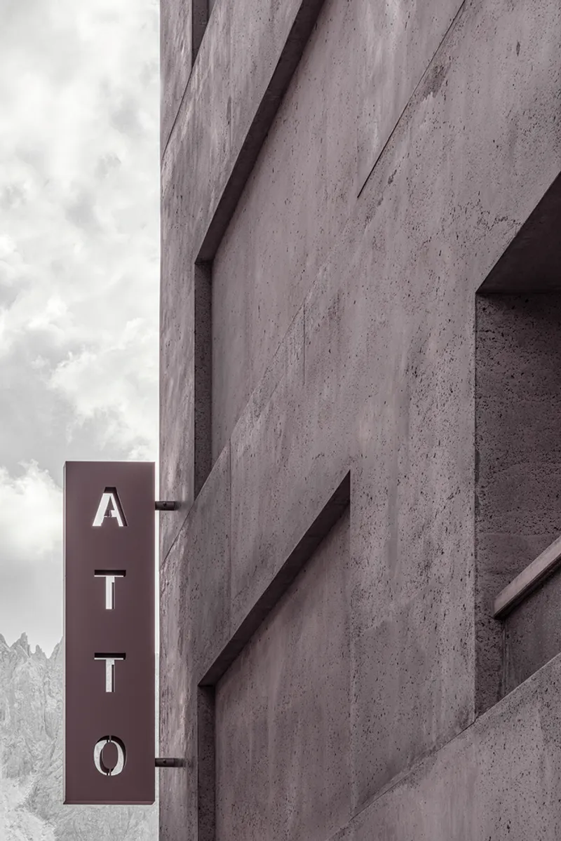 Close-up of the concrete gable edge with projecting signage bracket against a cloudy sky