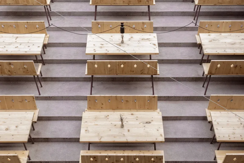 Top-down view of timber benches arranged in rows with diamond cutouts and terrazzo aisles between them