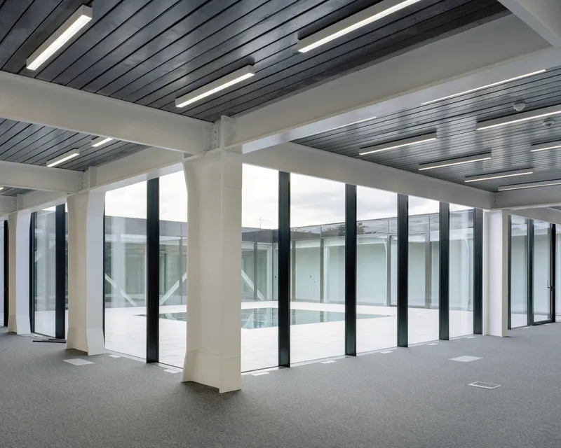 Interior perimeter with white columns and full-height windows framing views into a glazed courtyard