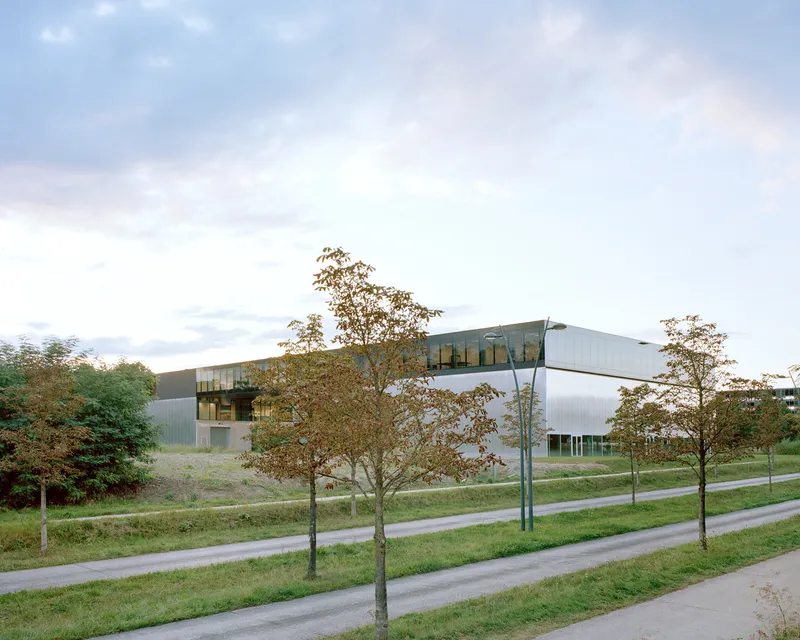 Exterior view of the cantilevered metallic-clad volumes set among trees at dusk