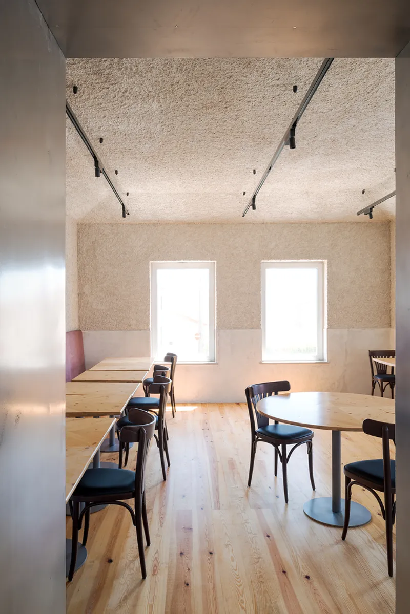Dining area with timber floor and bentwood chairs beneath an exposed concrete ceiling with metal bracing